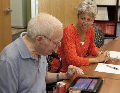 A man and woman looking at tablet on table.