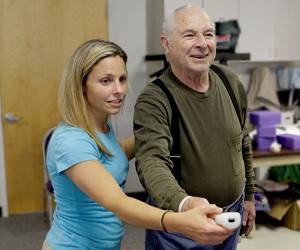 Female physical therapist working with an older patient to build arm strength.