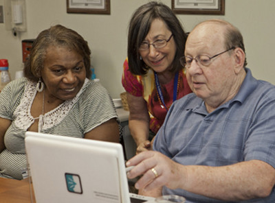 Three individuals looking at a computer screen together.